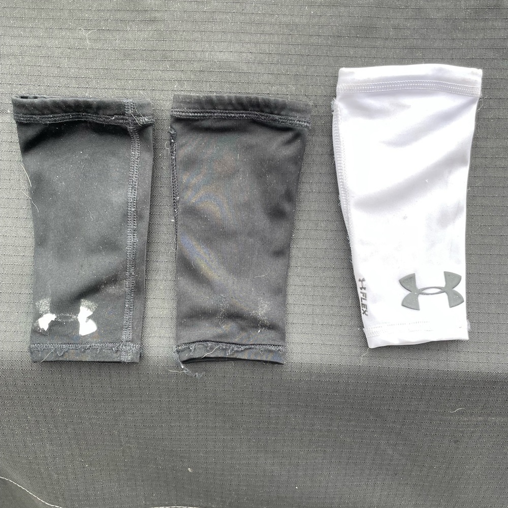 YS UnderArmour forearm pads for football. 2 black and one white.